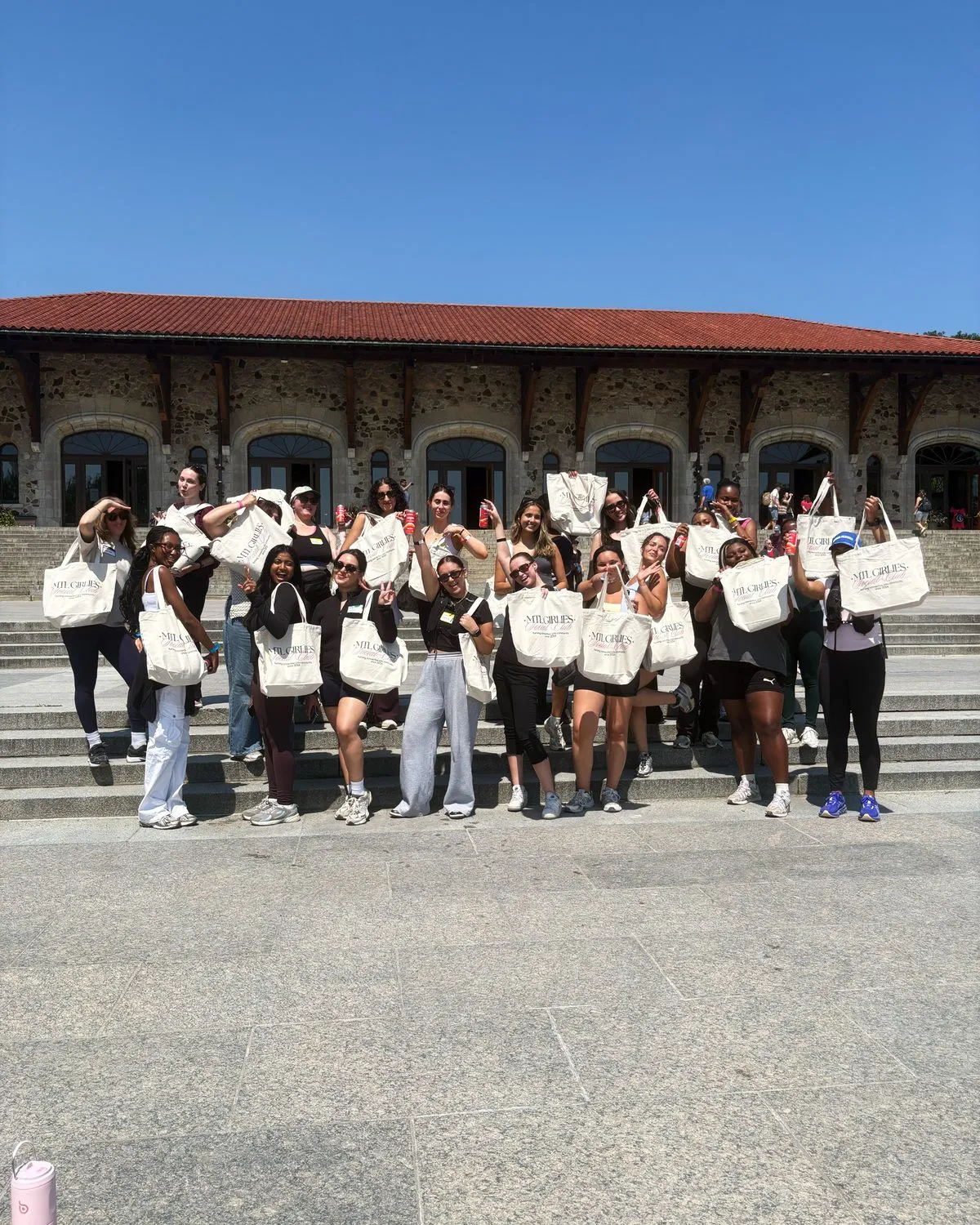 The group on the chalet steps holding their MGS totes up