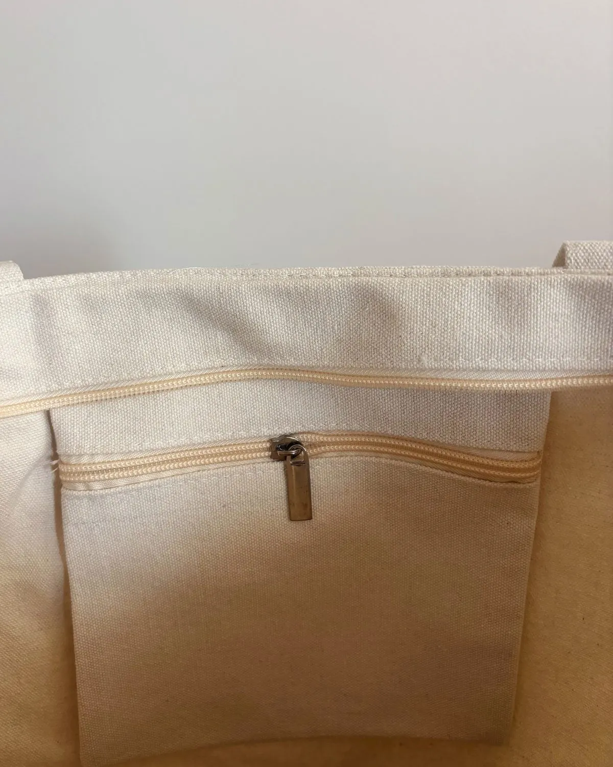 Close-up of the tote’s zippered top and inner slip pocket